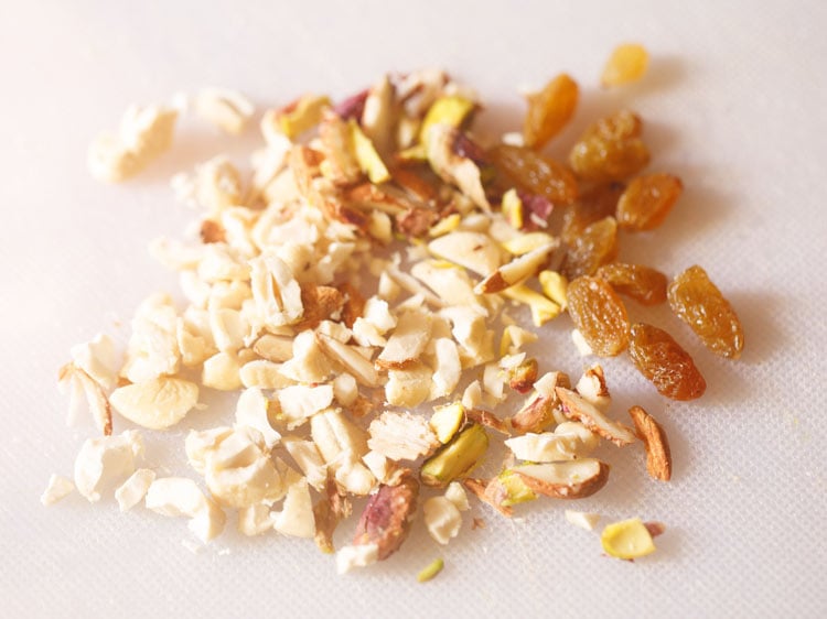 nuts like cashews, almonds and pistachios being chopped in a tray.