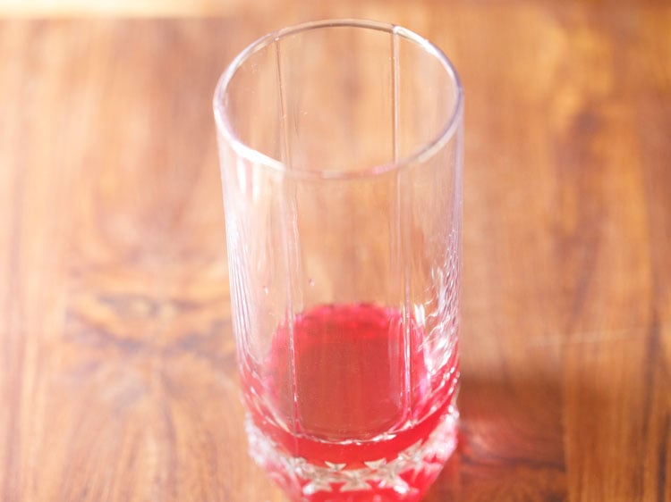 adding rose syrup in a glass