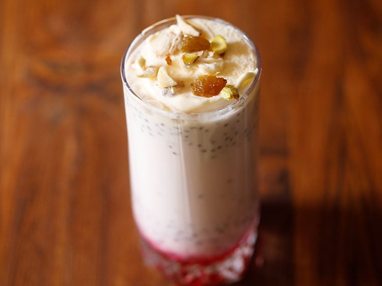 Pink layered ice cream drink with chopped nuts on top.