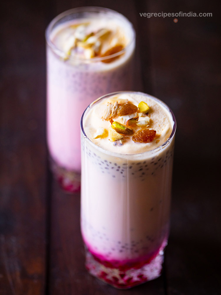 Pink layered ice cream drink with chopped nuts on top.