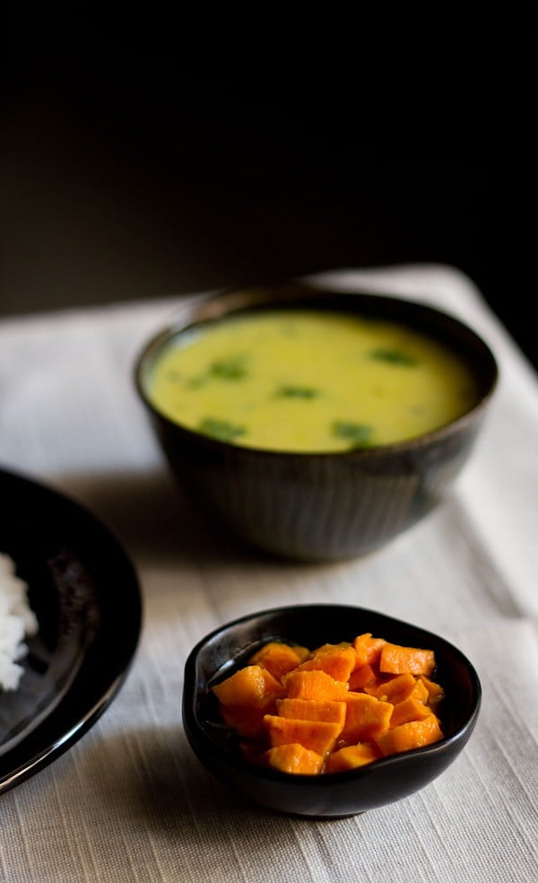 turmeric pickle in a small black bowl with a side of rice and curry