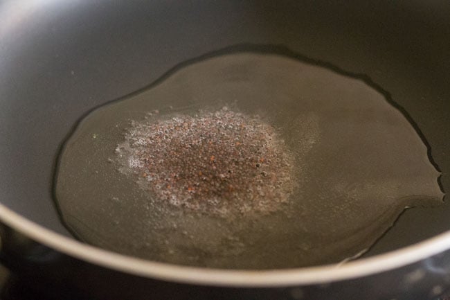 mustard seeds added to hot oil or ghee in pan. 