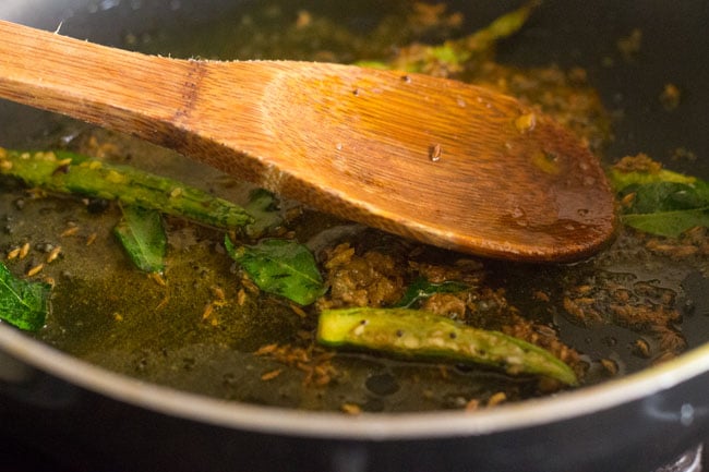 mixing spice powders with the rest of the ingredients in the pan. 