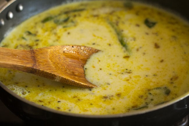 stirring the kadhi mixture with the spices. 