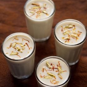 piyush drink garnished with saffron and pistachios and served in 4 glasses.