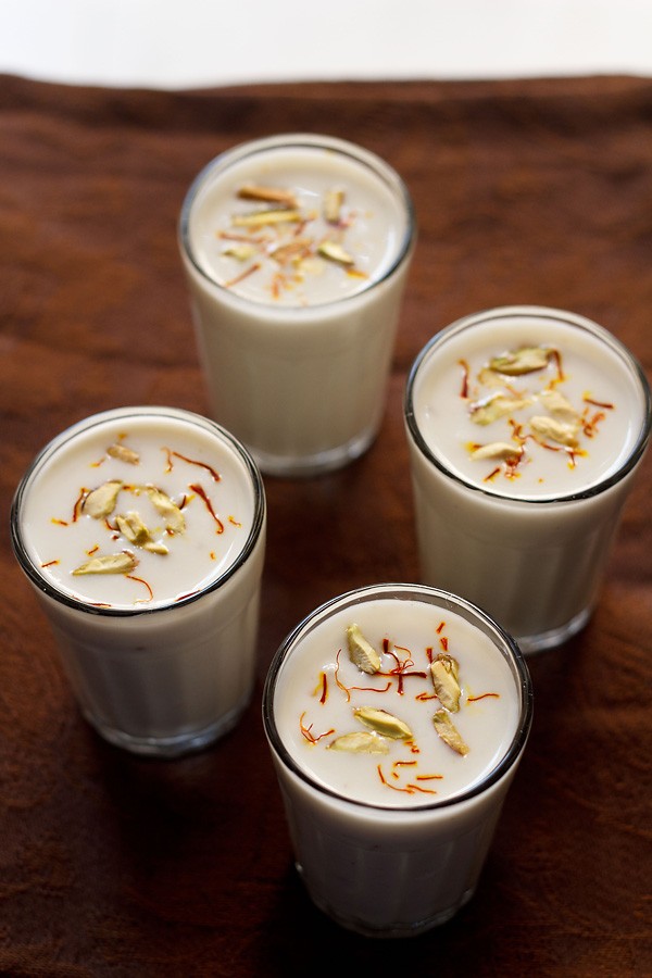 piyush drink garnished with saffron and pistachios and served in 4 glasses.