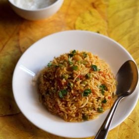 tawa pulao served in a white plate with a spoon kept in the right side on the plate.