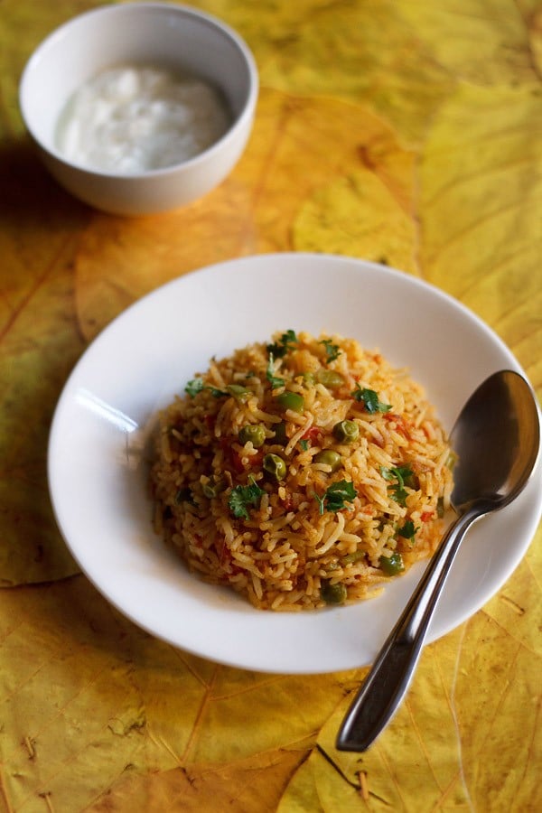 tawa pulao served in a white plate with a spoon kept in the right side on the plate.