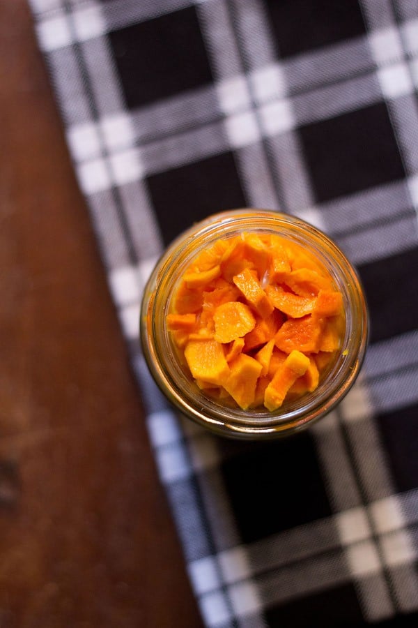 turmeric pickle or haldi ka achar in a jar on a checkered table cloth. 