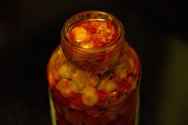 spooning the star gooseberry pickle in a sterilized glass jar. 