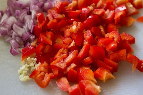 chopped onions, red bell peppers and garlic cloves for making stuffing for calzone pocket. 