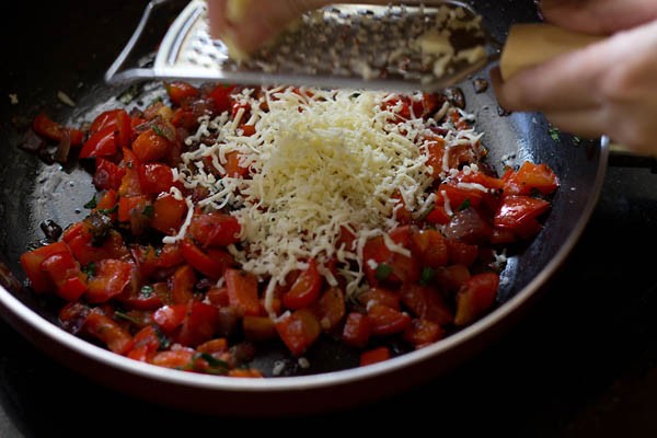 grating cheese on cooked stuffing mixture for calzone pocket. 