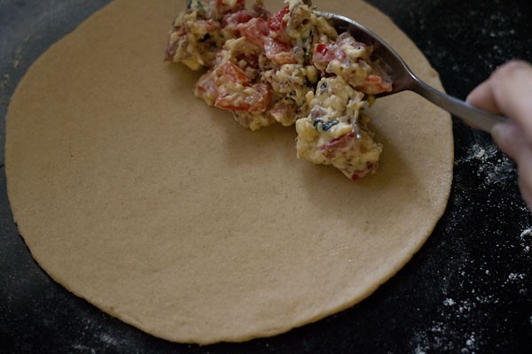 adding prepared stuffing mixture on one side of the rolled dough chapatti. 