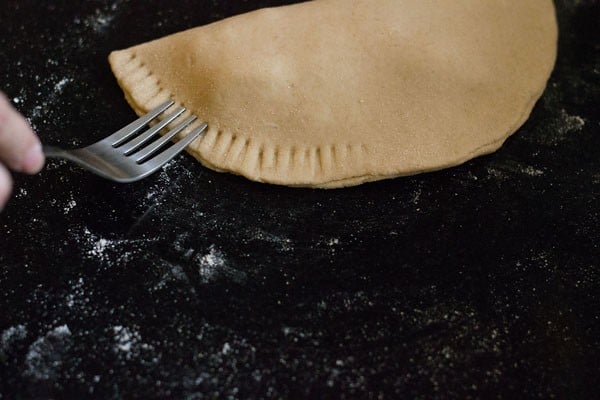 pressing the edges with a fork to seal the calzone. 