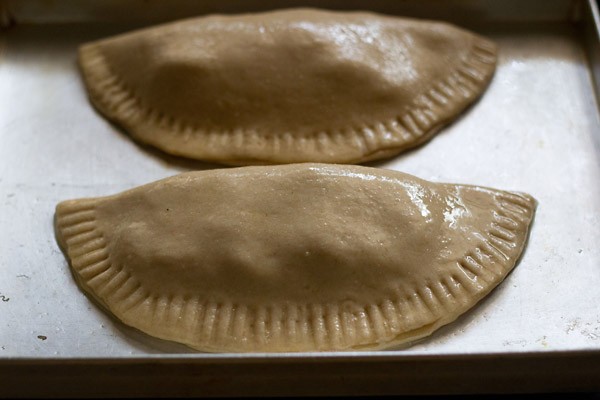 calzones placed in a greased baking tray. 