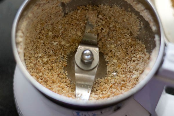 in a grinder grind the almonds, cashews, raisins to a semi fine powder