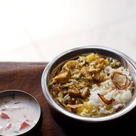 kathal biryani served in a copper handi with a bowl of raita kept on the left side.