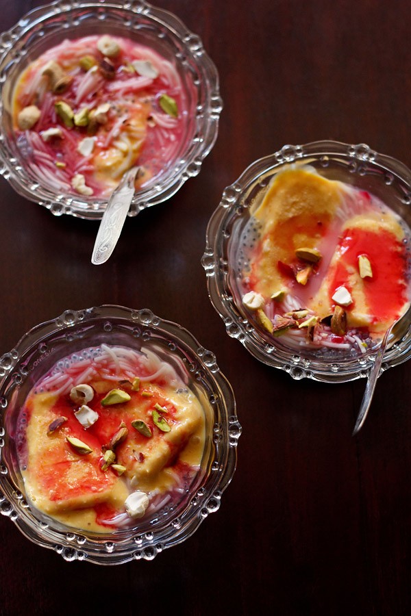 top shot of kulfi falooda served in 3 glass bowls with spoons in 2 of them. 