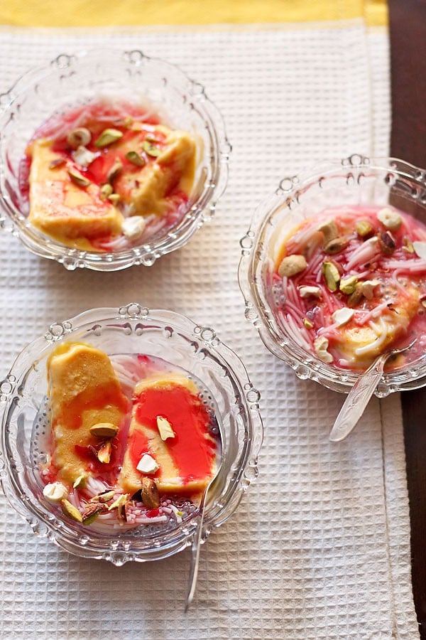 kulfi falooda served in 3 glass bowls with spoons in 2 of them.