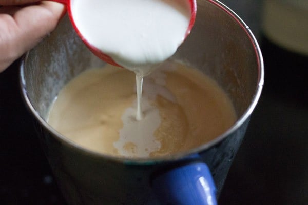 cream being poured in the blender with a red measuring cup