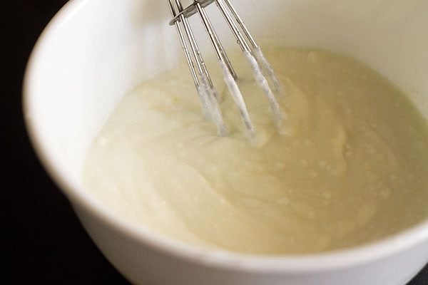whisking curd in a white bowl