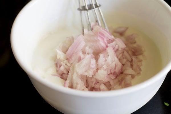 adding chopped onions to the curd for onion raita