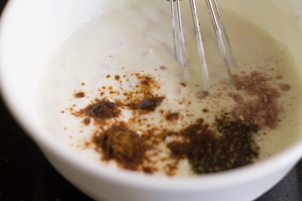 adding cumin powder, black pepper powder and black salt to the curd for onion raita