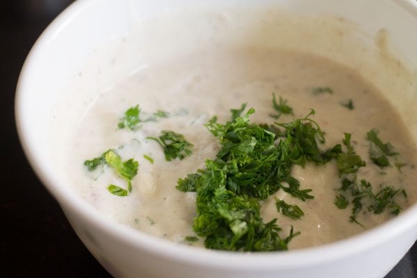 adding chopped coriander leaves to the curd