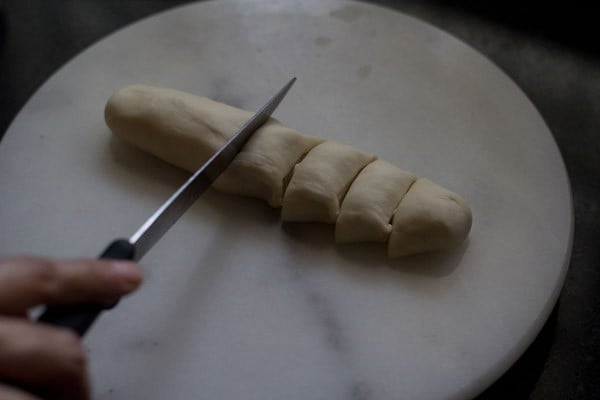 cutting a log of dough with knife