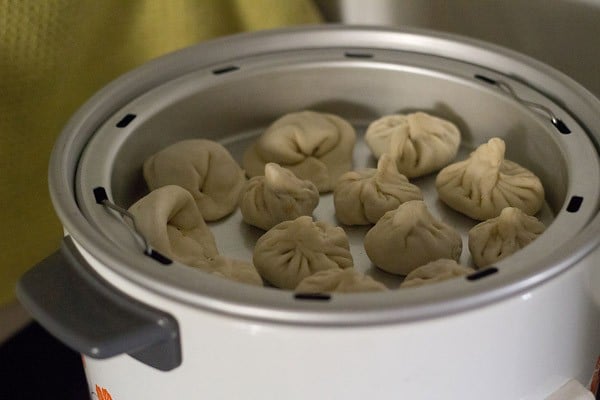 the steamer pan with the veg momos kept inside an electric cooker for steaming