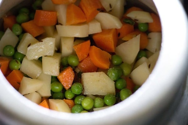 chopped vegetables, green peas and asafoetida added to the pressure cooker. 