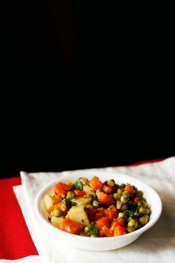 aloo gajar matar served in a white bowl. 