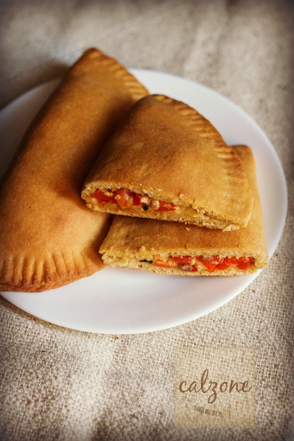 a whole calzone and a halved calzone served on a white plate with text layover. 