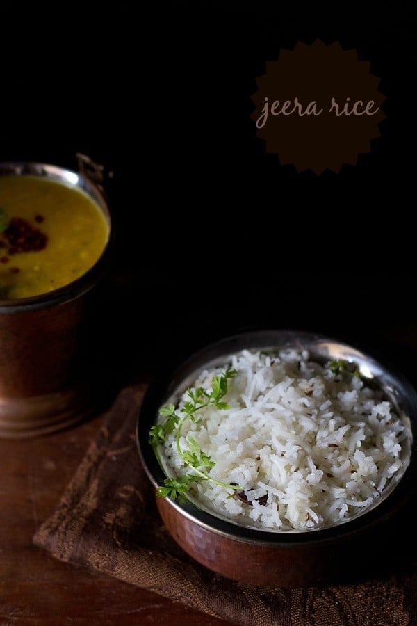 easy cumin rice in a brown and silver bowl garnished with a sprig of fresh cilantro