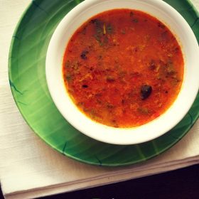 katachi amti served in a white bowl placed on a green plate with text layover.