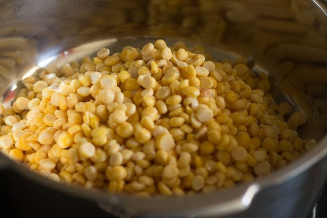 Add the soaked and drained chana dal to the pressure cooker. 