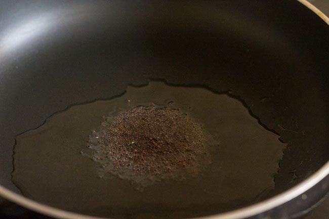 mustard seeds added to hot oil in pan. 