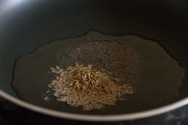 Add the cumin seeds to the hot oil in the pan. 