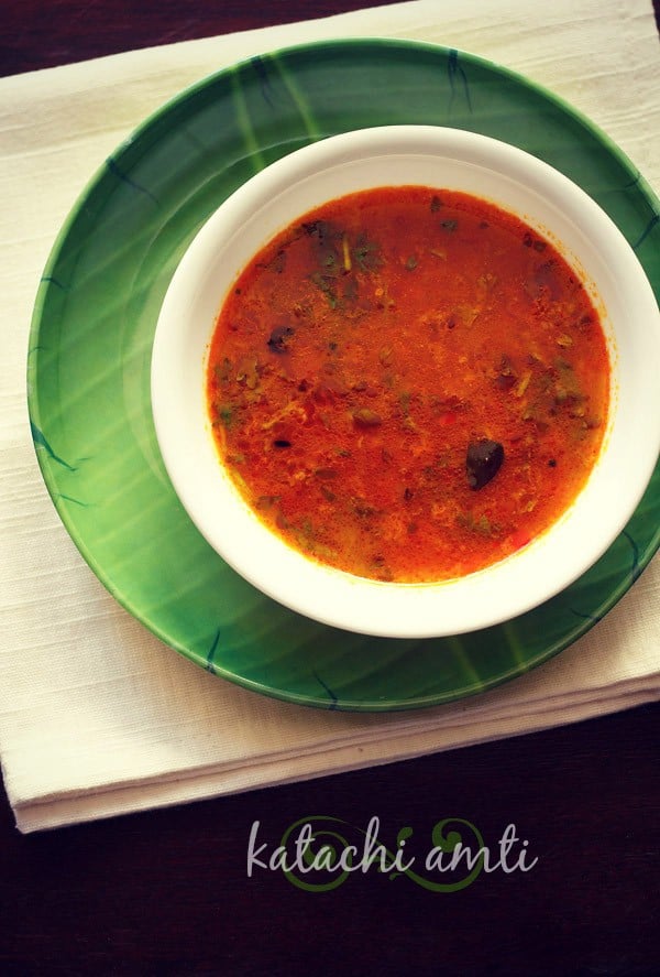 katachi amti served in a white bowl placed on a green plate with text layover.