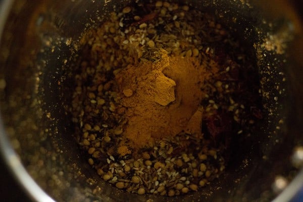 grinder jar filled a quarter of the way with roasted spices.