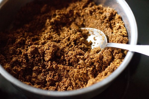 ground Maharashtrian goda masala in a silver bowl with a silver spoon.