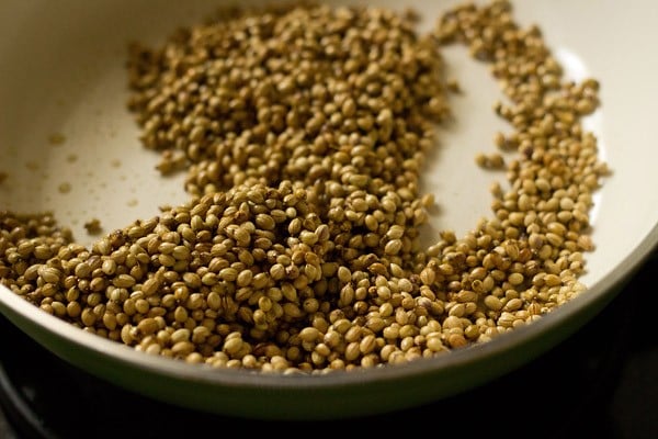 roasting coriander seeds in oil on the stovetop.