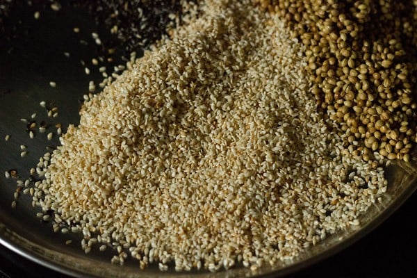 roasted sesame seeds and coriander seeds on a plate for making goda masala.