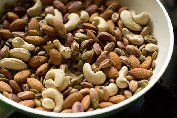 dry roasting dry fruits and seeds in a pan for making masala doodh powder. 