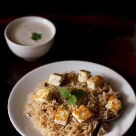 paneer pulao served on a white plate with a side of raita