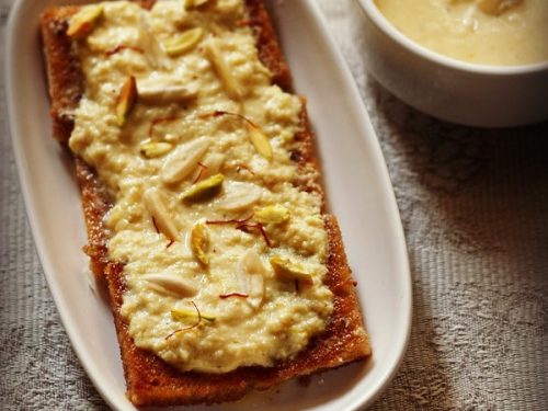 shahi tukda in a white oblong serving plate with a bowl of homemade rabri
