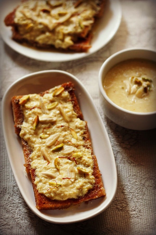 shahi tukda in a white oblong serving plate with a bowl of homemade rabri