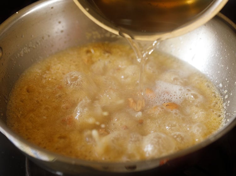 pouring hot bubbling sugar solution in the fried rava mixture