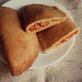 a whole calzone and a halved calzone served on a white plate with text layover.