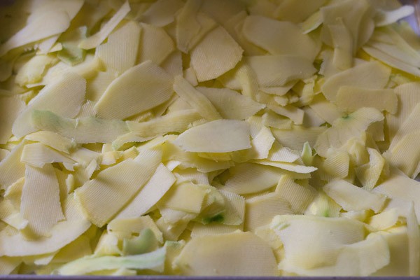 raw mango strips spread on a plate for drying. 